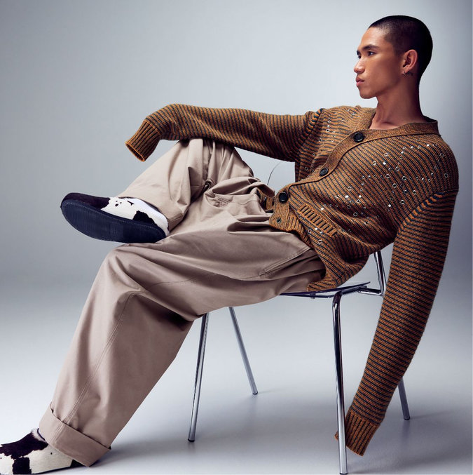 Jeune homme portant un cardigan rayé, un pantalon large et des mules motif vache de la marque Marni.