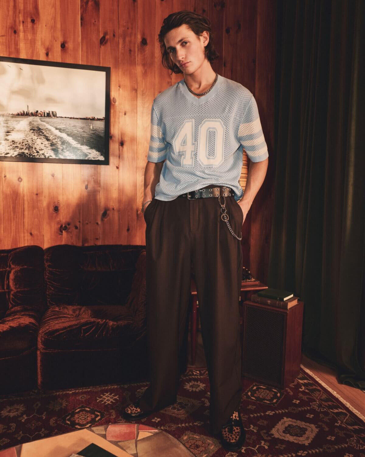 A young man wearing dark brown, wide-leg pleated trousers