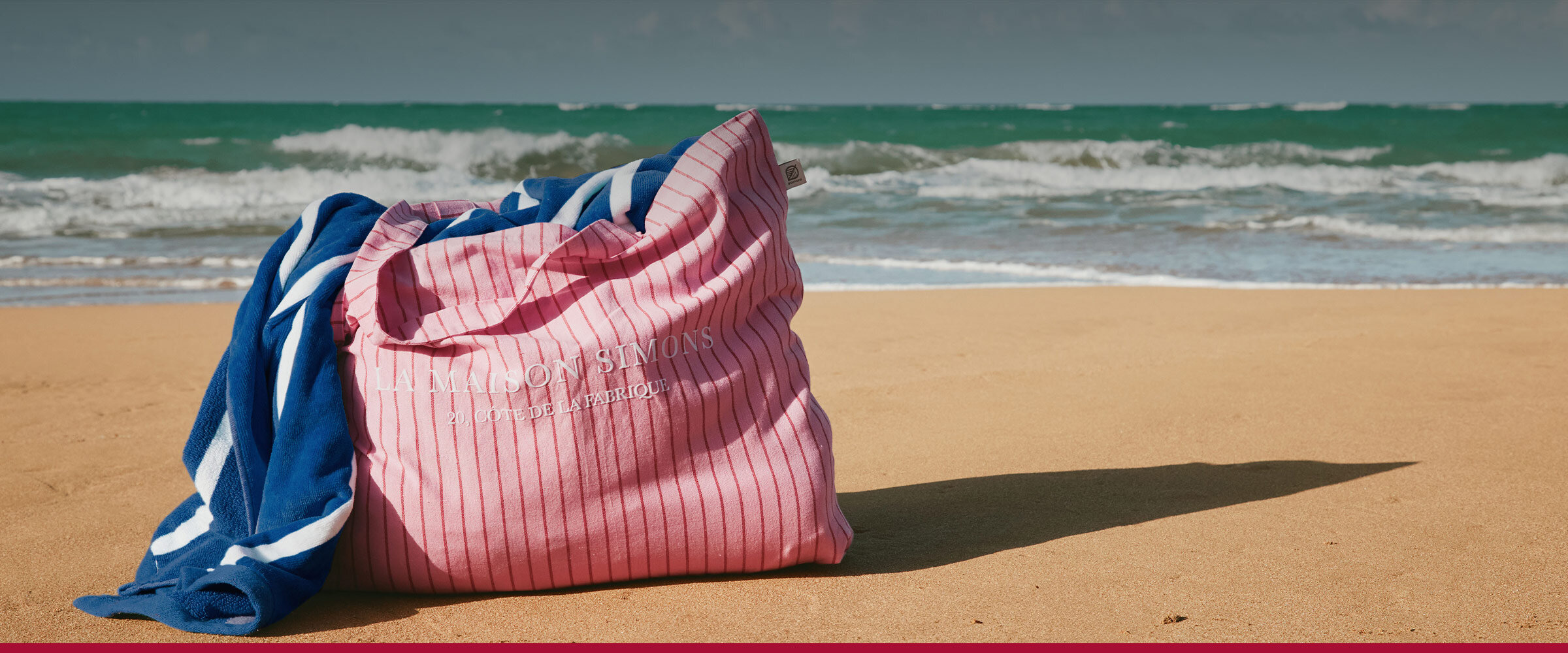 A pink bag by La Maison Simons left on a beach