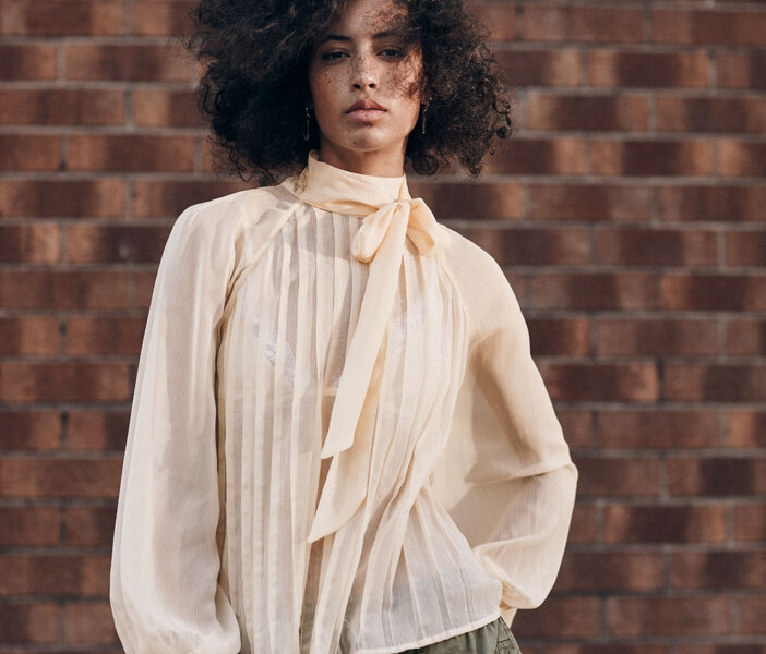 femme portant une blouse crème avec un col foulard