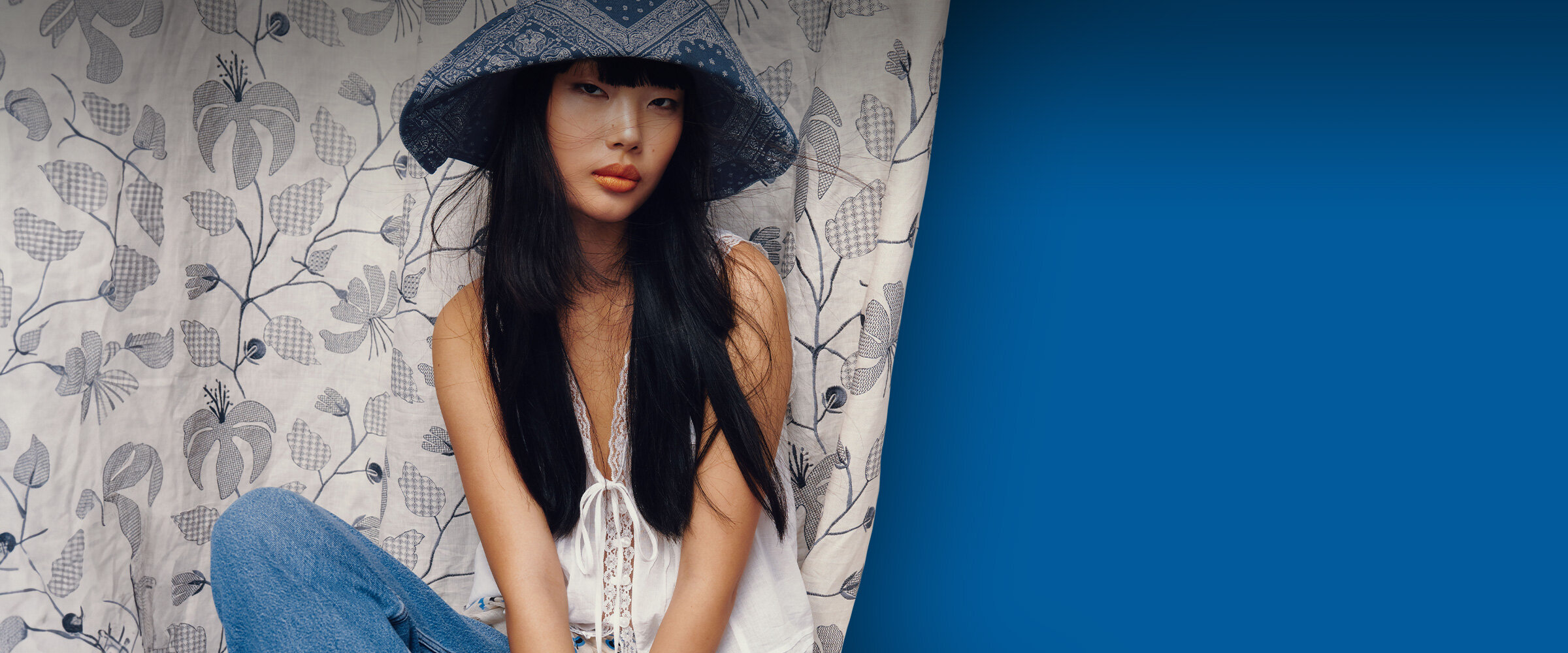 Jeune femme qui porte un grand chapeau sur un fond bleu