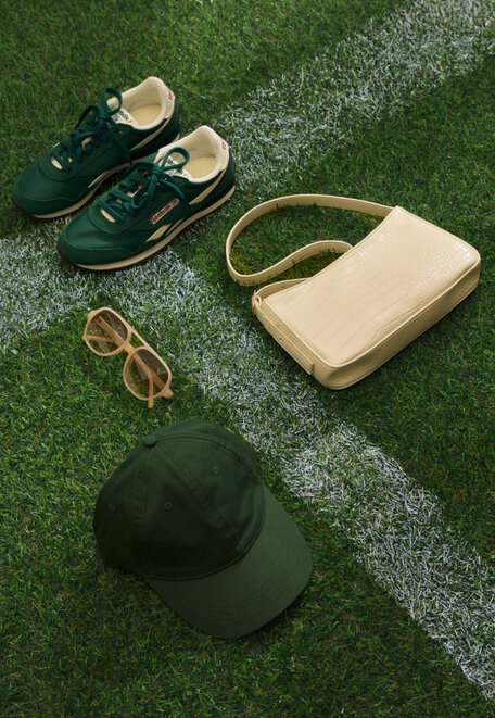 Sneakers, glasses, handbag and cap on a soccer field