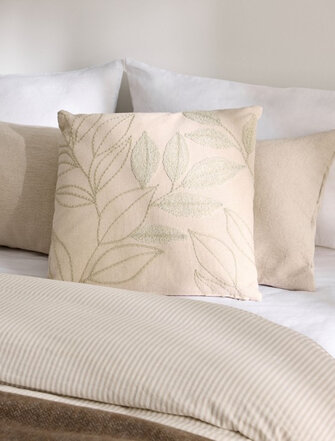 Coussin de couleur crème avec un motif de feuillage délicat