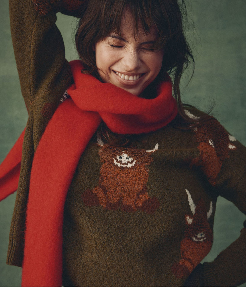 Young woman wearing a sweater and a red scarf.