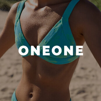 Une femme sur la plage portant un maillot deux-pièces au motif floral de la marque OneOne