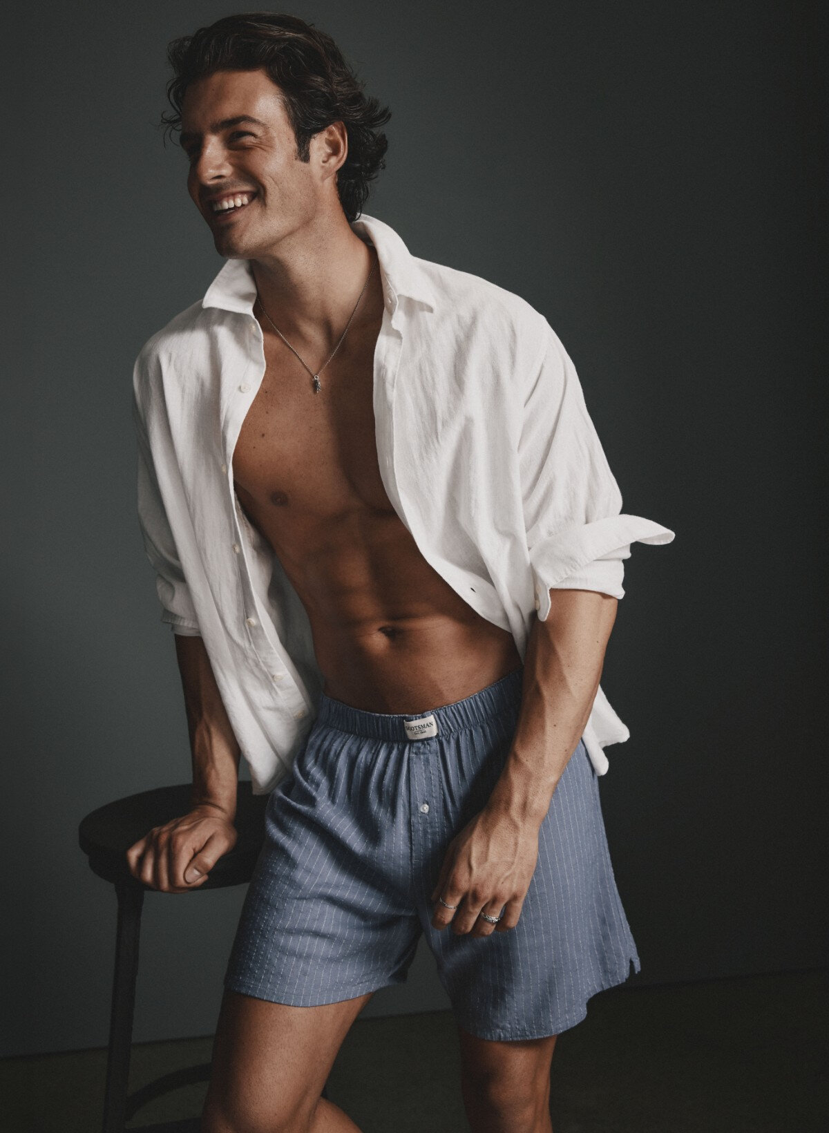 A man is wearing a white shirt and striped boxer shorts.