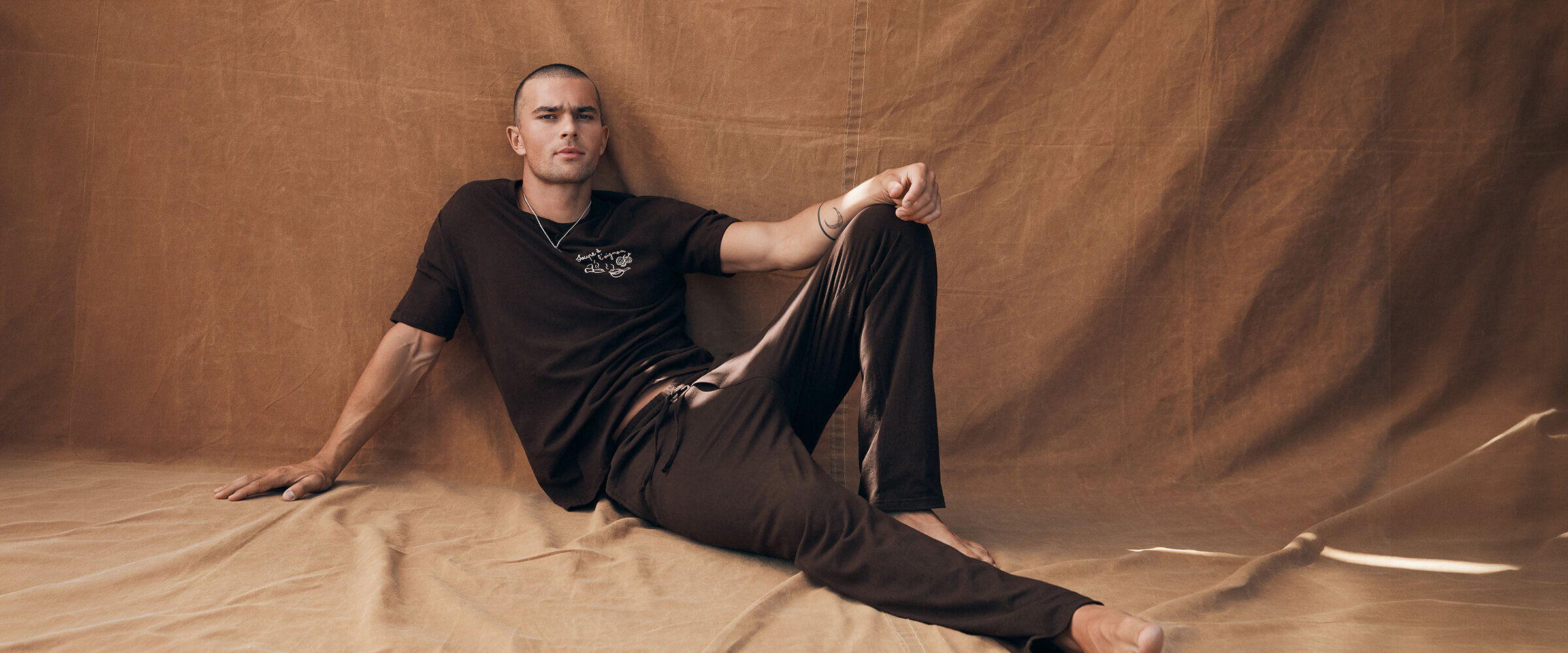 Homme vêtu d'un t-shirt et d'un pantalon détente brun foncé