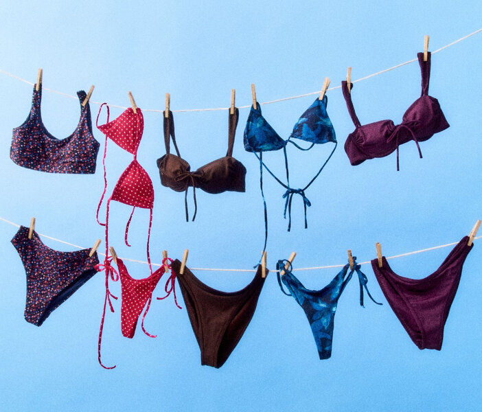 A selection of two-piece swimsuits of different styles and colors hanging on a clothes line.