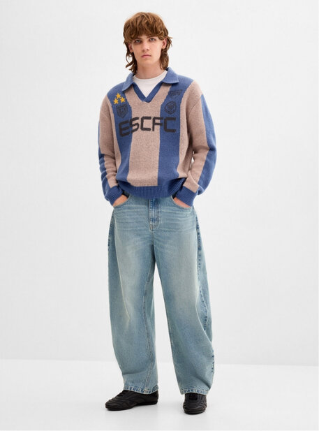 Jeune homme portant un pull rayé et un jean ample bleu