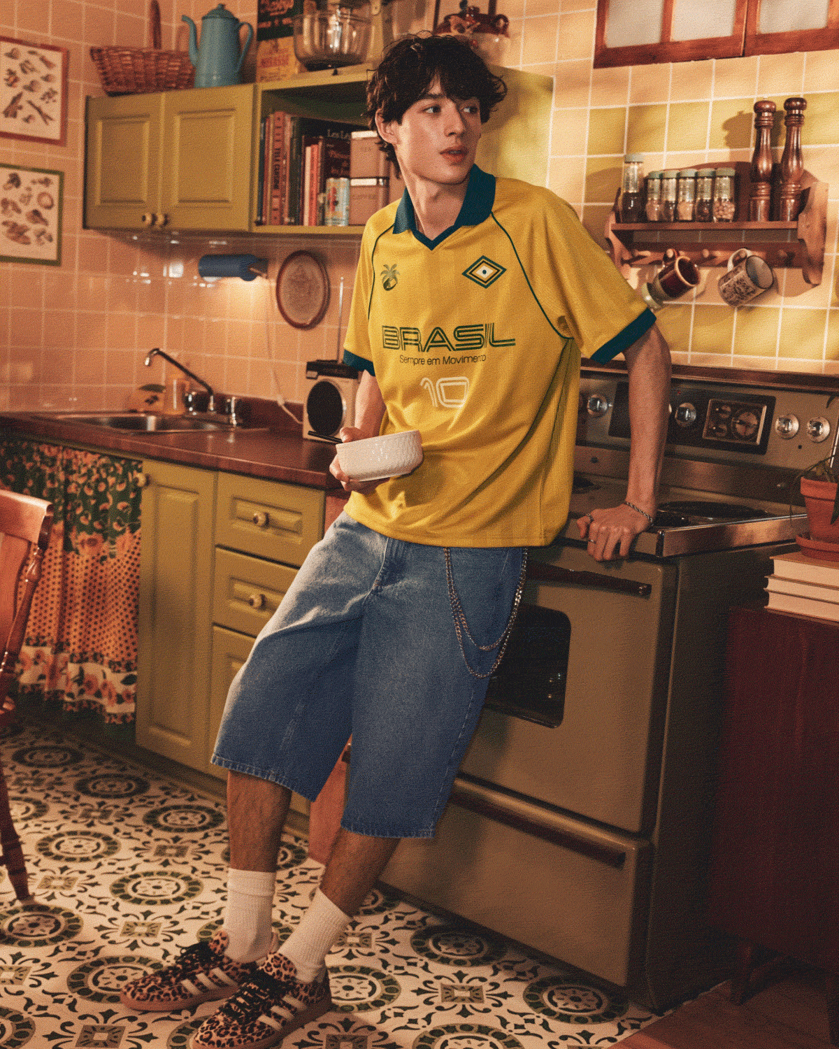 A young man wearing a soccer jersey-style polo shirt and baggy denim shorts