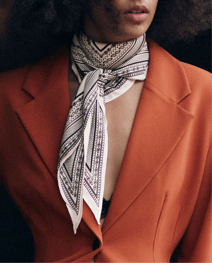 Femme portant un foulard blanc à motif noir noué au cou