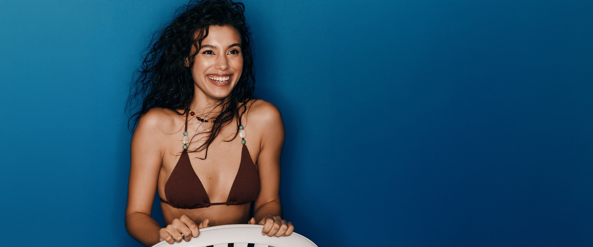 Femme portant un haut de bikini triangle brun orné de billes et de pierres