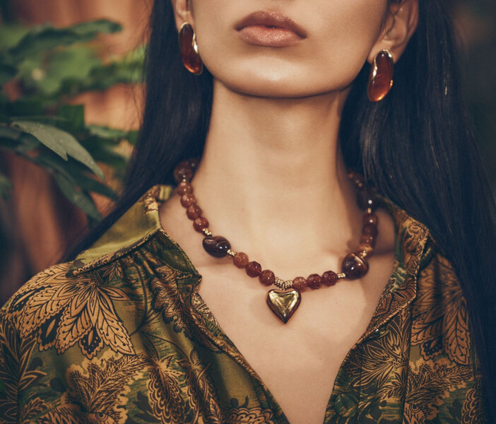 A woman wearing a large necklace made of natural stones in shades of amber