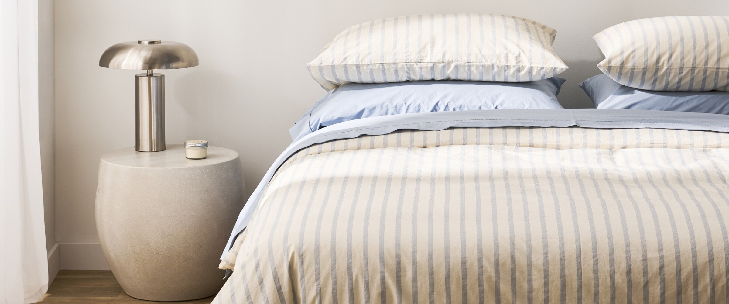 Bed with a striped duvet cover and light blue sheets