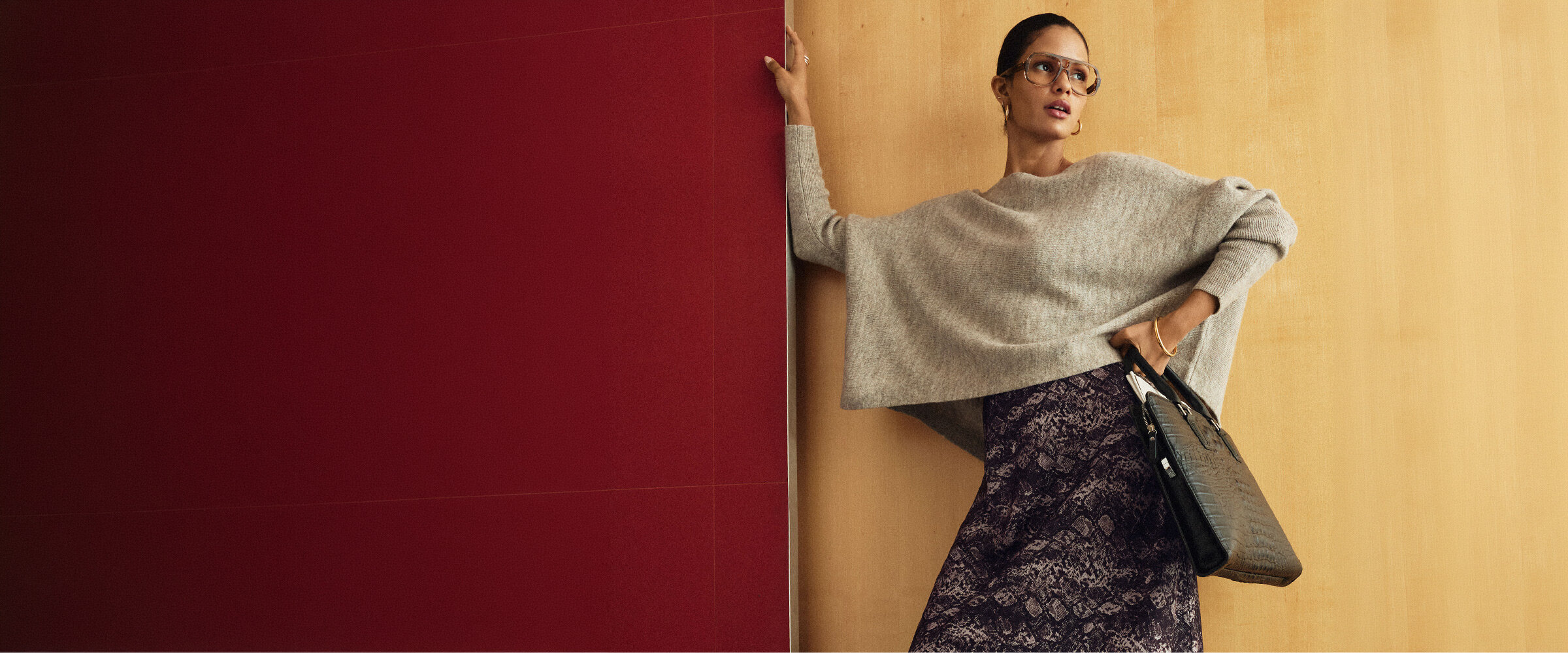 Woman wearing a snake-print satiny skirt with an oversized sweater