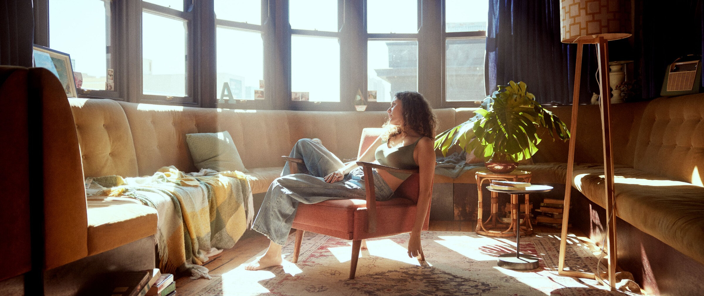 Young woman sitting in front of a sunny window in a cozy apartment setting