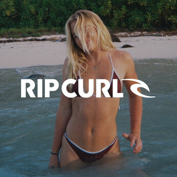 Jeune femme se baignant dans la mer porte un maillot de bain deux-pièces de marque RipCurl brun et bleu