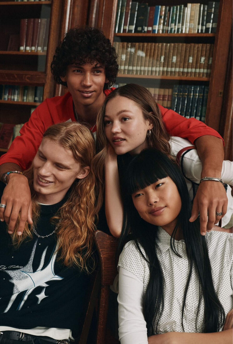 A group of two young men and two young women wearing academic-style clothing