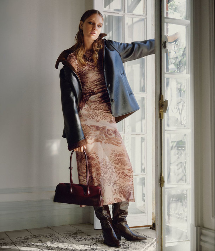 Woman wearing a sheer, fitted dress and a leather jacket.