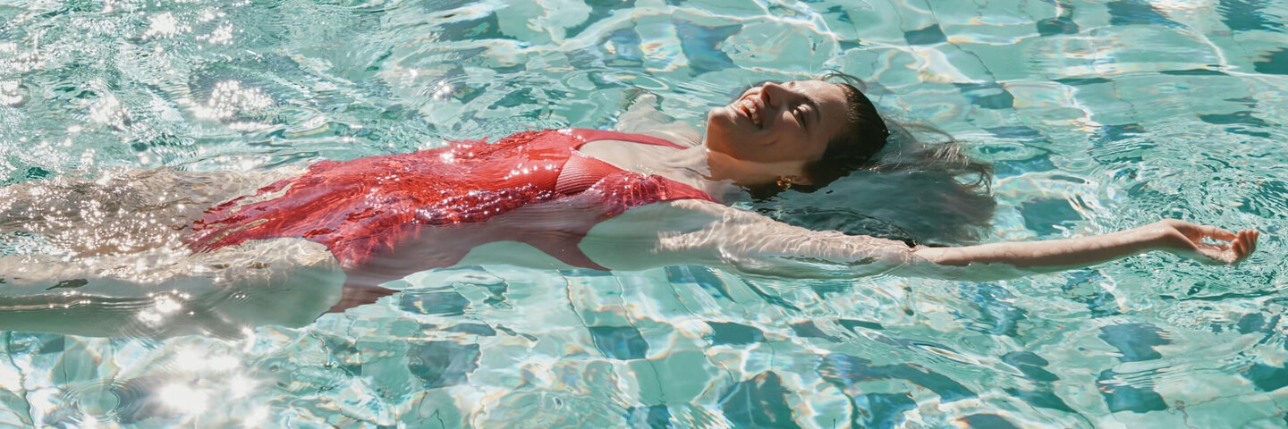 Young woman wearing s red swimsuit swimming in a pool.