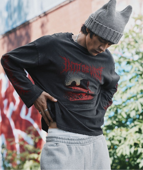 Man in a grey beanie wearing a black T-shirt with a red graphic over a black long-sleeve top.