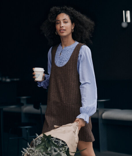 Women with coffee wearing a brown dress overlaid on a blue blouse