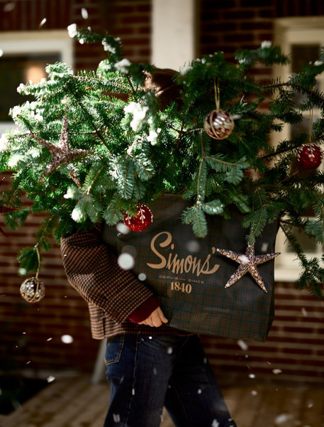 Somebody moving a Christmas tree in a Simons bag