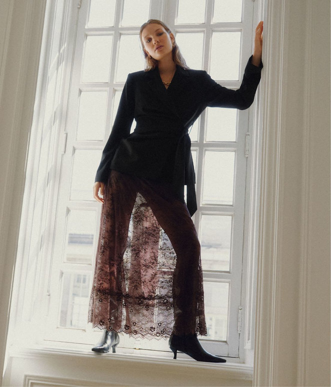 Woman wearing a lace skirt and a wrap-style jacket.