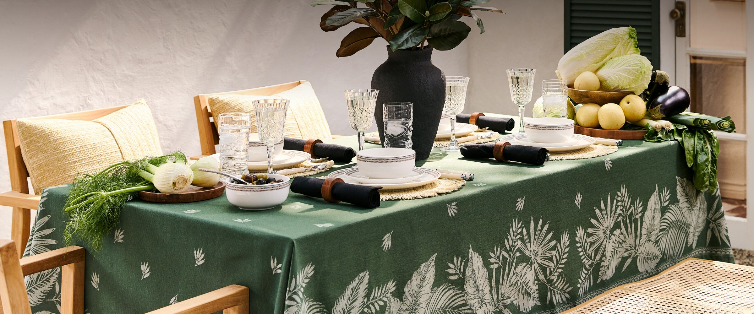 Une table avec une nappe verte, des verres et des assiettes