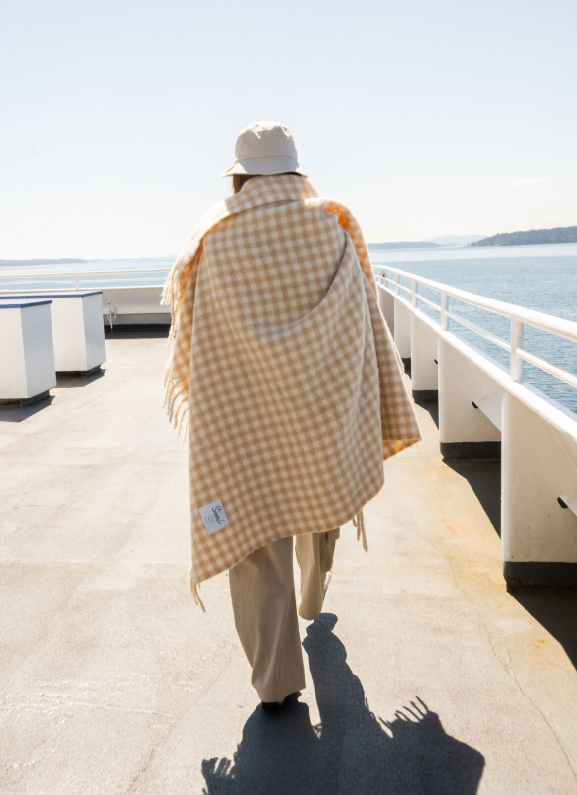 Femme sur un bateau avec une couverture à carreaux sur les épaules