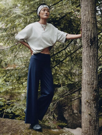 Femme portant un sweat gris prenant une pause en s'appuyant sur un arbre